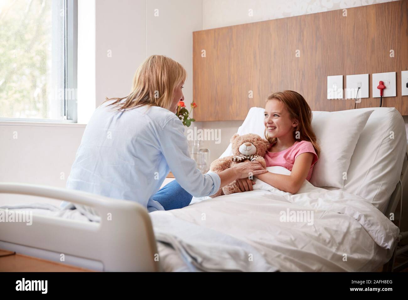 Mother Visiting Daughter Lying In Bed In Hospital Ward Stock Photo