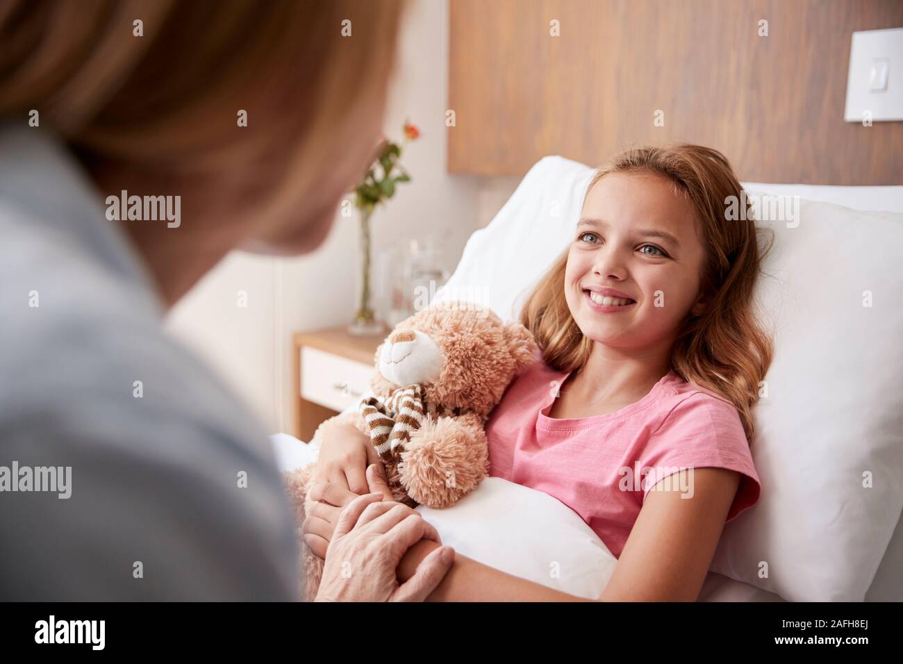 Mother Visiting Daughter Lying In Bed In Hospital Ward Stock Photo