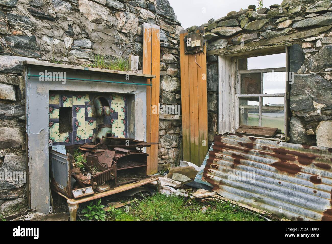 Tiled area with flue and rusting cooker in an abandoned crofters house, Isle of Lewis and Harris, Outer Hebrides, Scotland Stock Photo