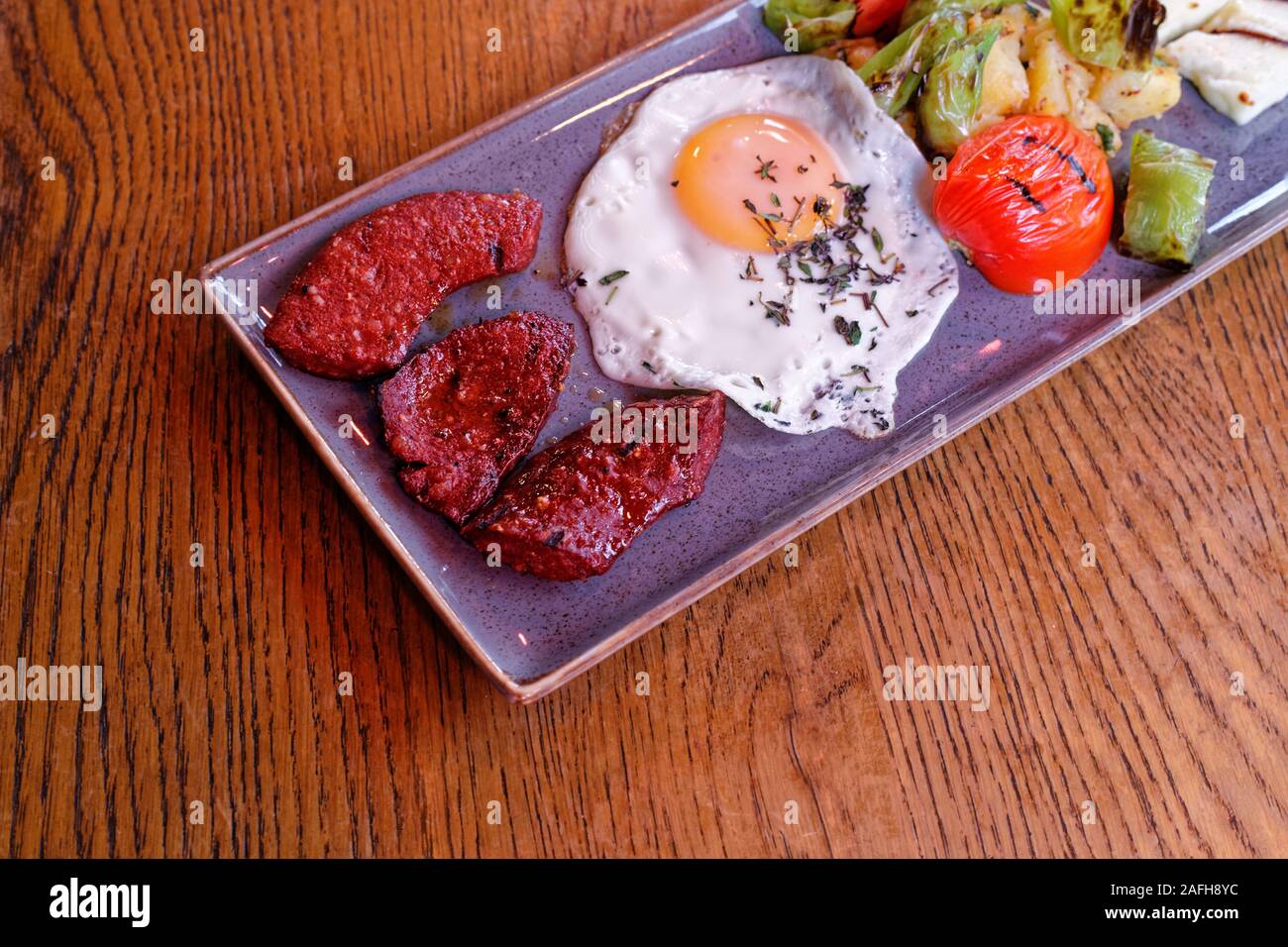 Turkish roasted breakfast plate with fermented bologna sausage (sudjuk), grilled egg, hallouim (hellim) cheese, boiled potatoe, green pepper and roast Stock Photo