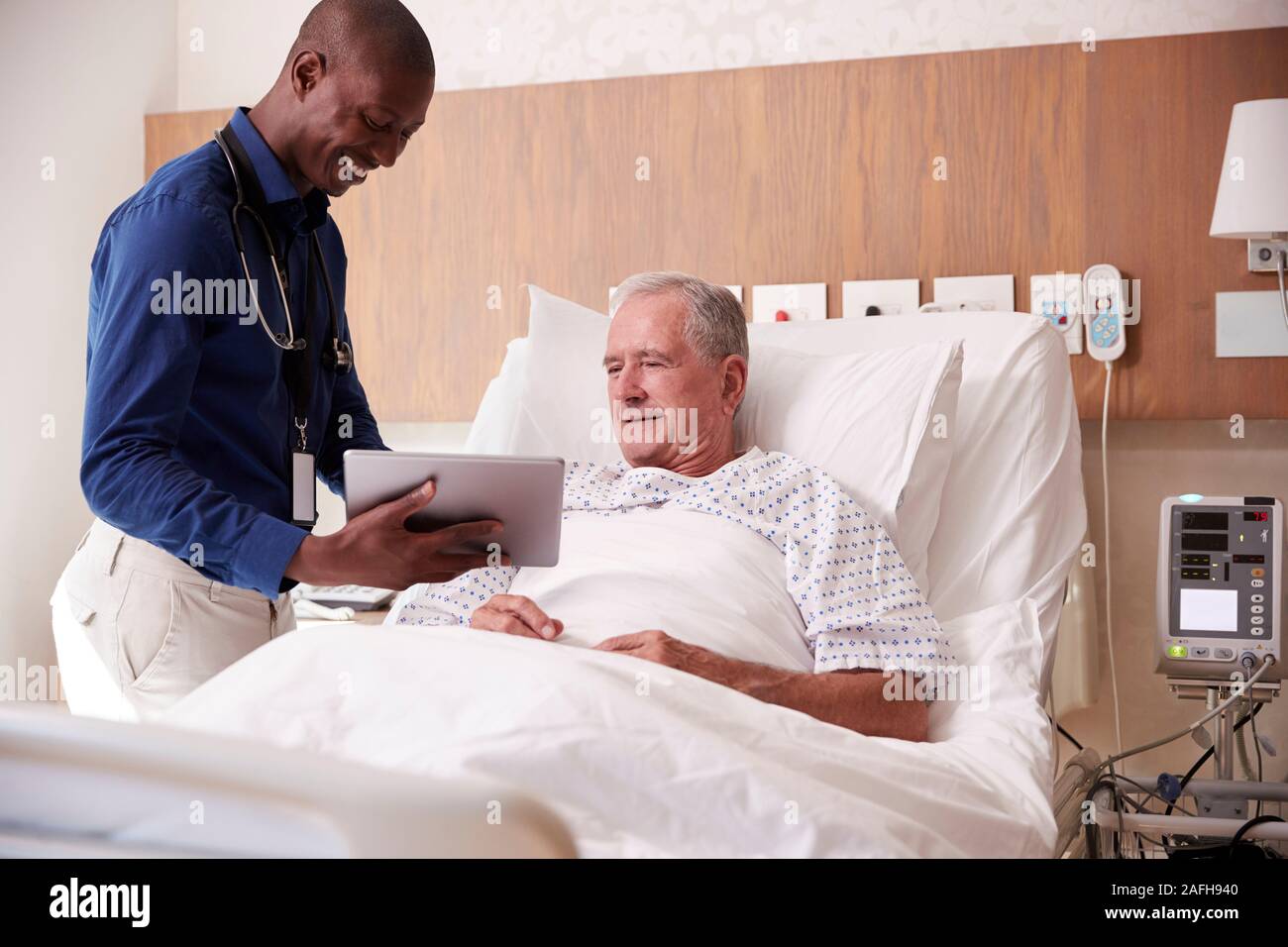 Doctor With Digital Tablet Visiting And Talking With Senior Male