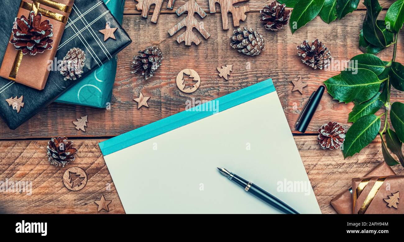 Christmas letter to Santa Claus concept. Flat lay composition with writing paper, pen, cone pines, wrapped gifts and xmas decoration. Stock Photo