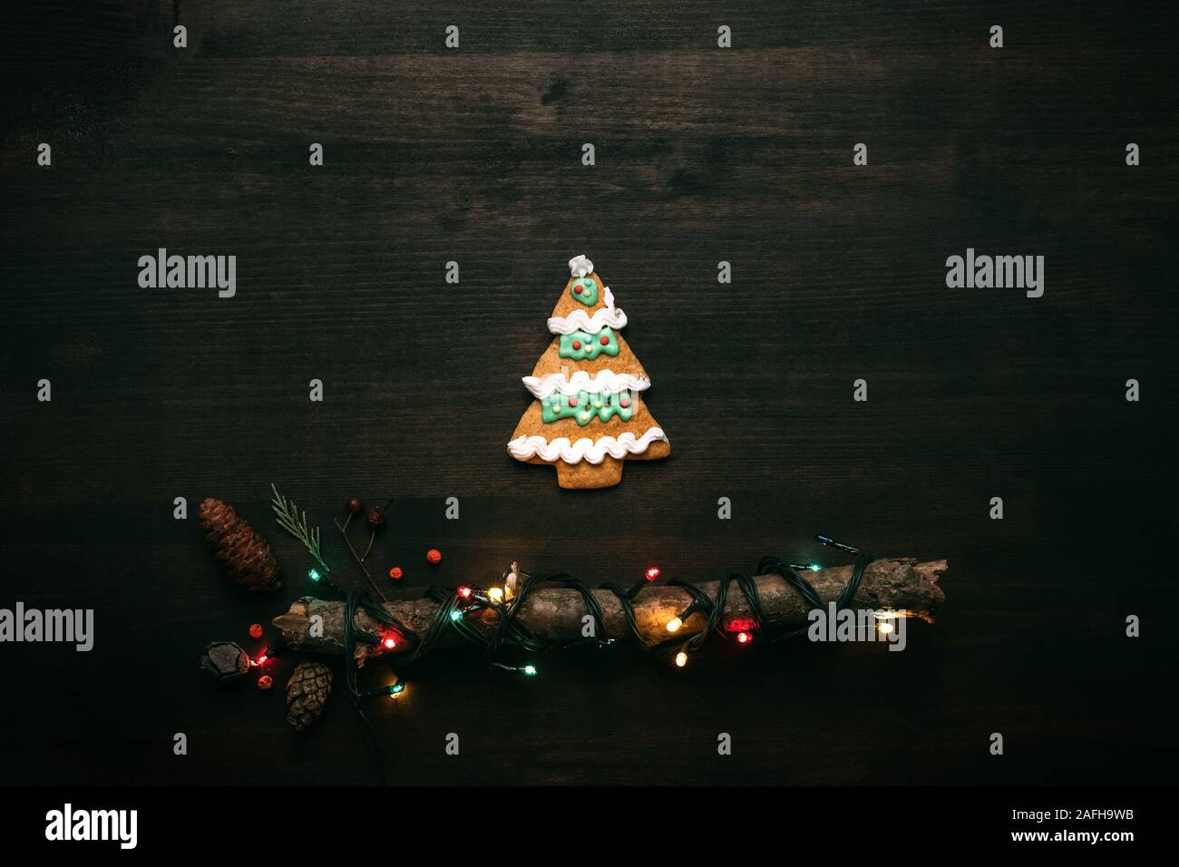 Merry Christmas flat lay top view background with gingerbread tree cookie and twinkle light on wooden board Stock Photo