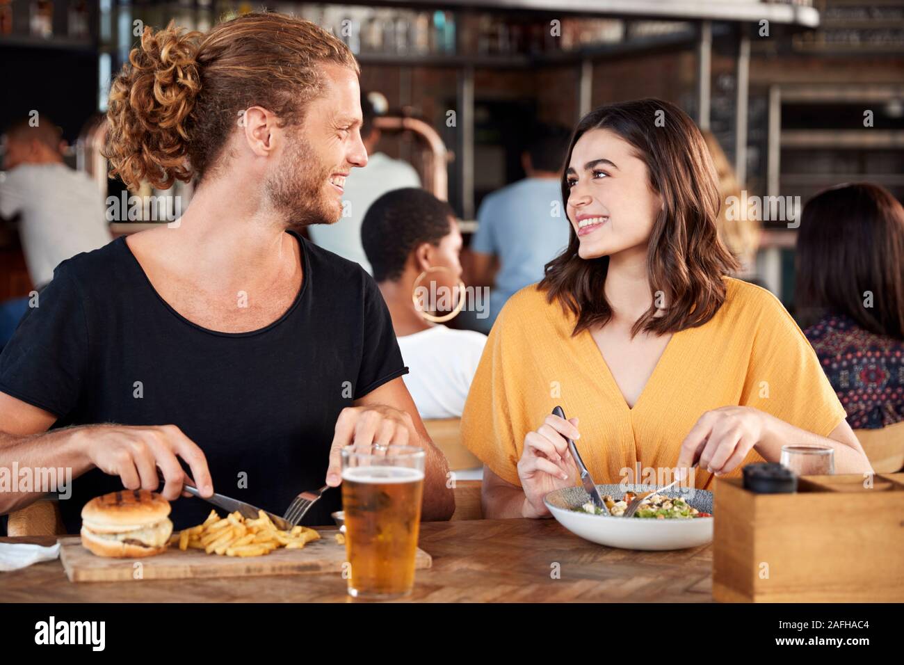 Couple On Date Meeting For Drinks And Food In Restaurant Stock Photo