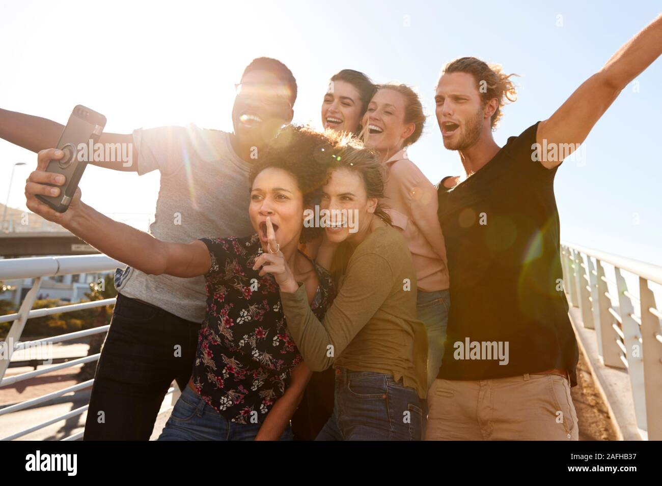 Smiling Young Friends Posing For Selfie On Outdoor Footbridge Together Stock Photo