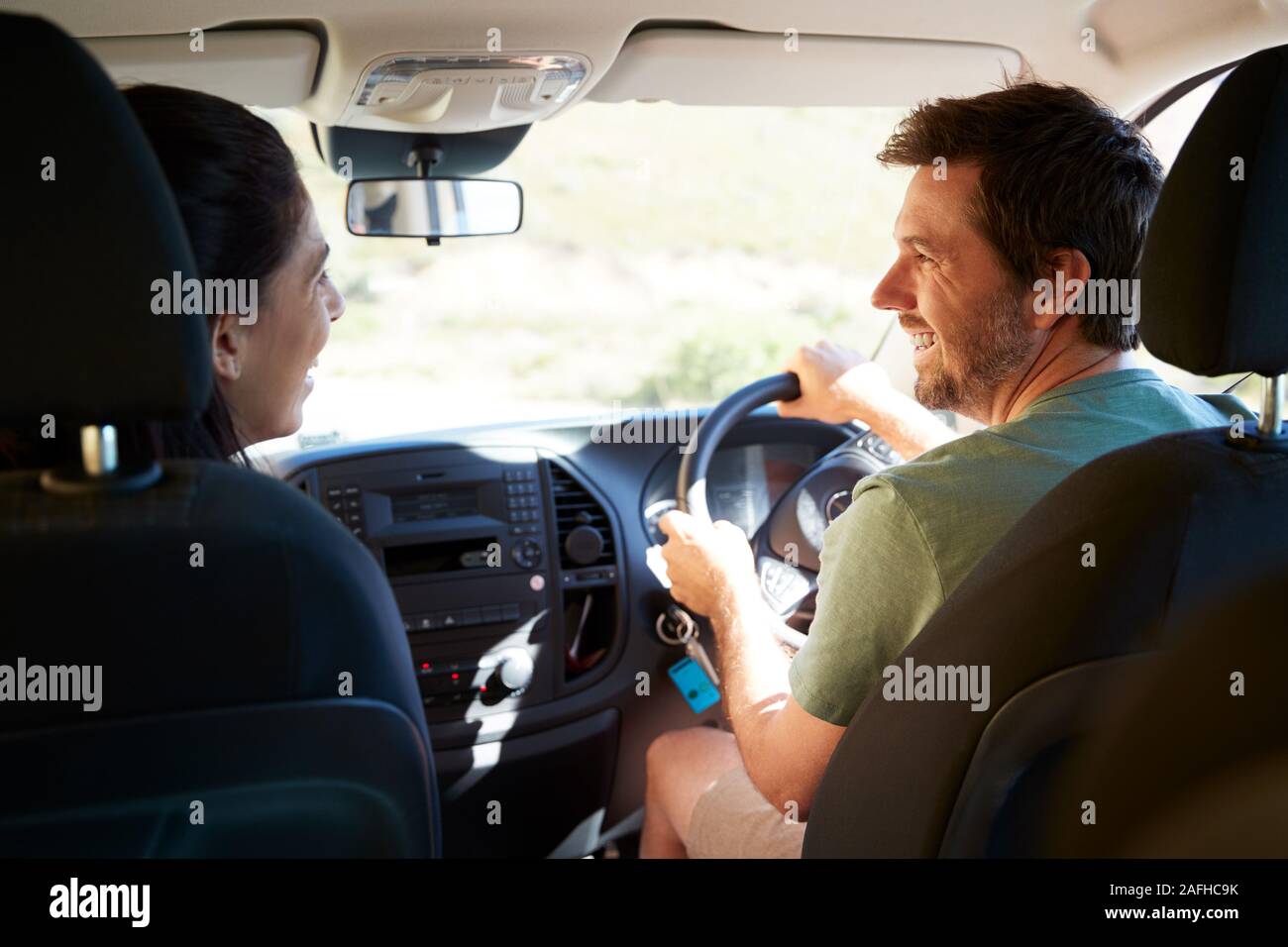Mid adult white couple driving in their car smiling at each other, back view, close up Stock Photo