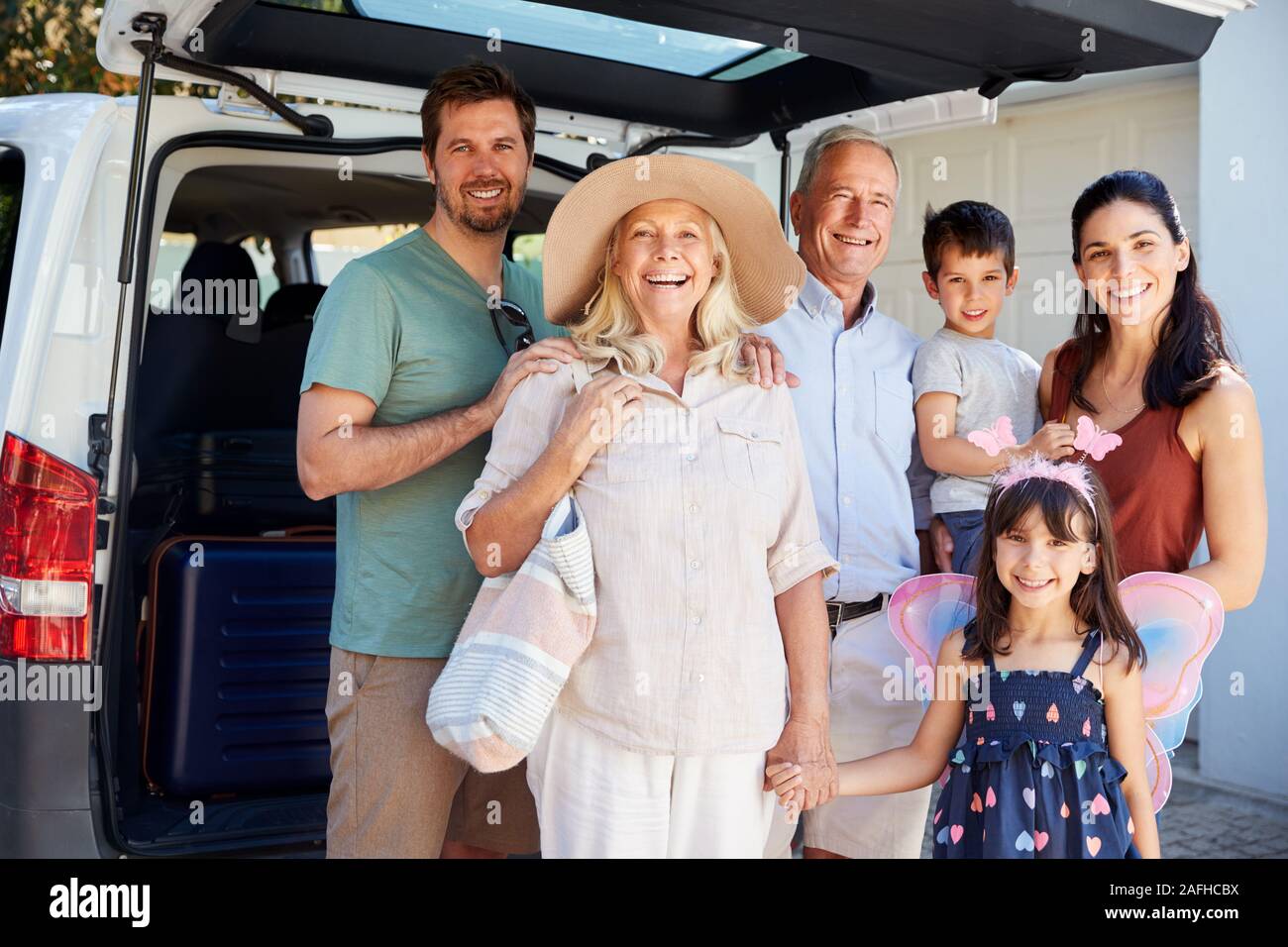 Three generation white family standing by car smiling to camera before leaving for vacation Stock Photo