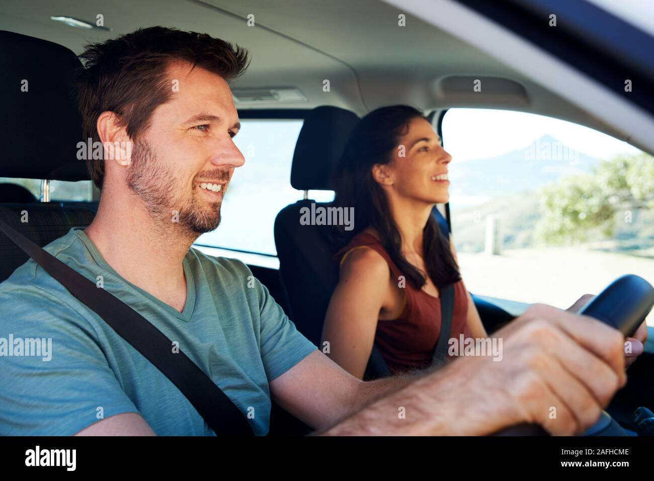 Mid adult white man driving car, his wife beside him in front passenger seat, close up, side view Stock Photo