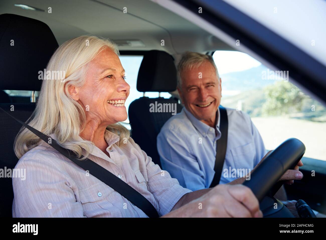 Senior white woman driving car, her husband beside her in front passenger seat, close up, side view Stock Photo