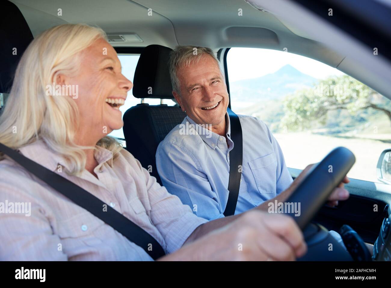 Senior white woman and her husband driving in their car laughing together, close up, side view Stock Photo