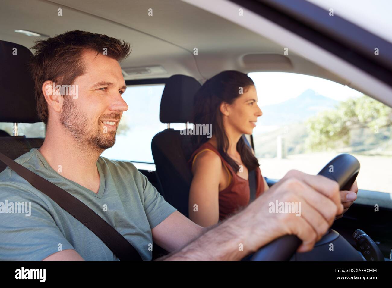 Mid adult white man driving car, his wife beside him in front passenger seat, close up, side view Stock Photo