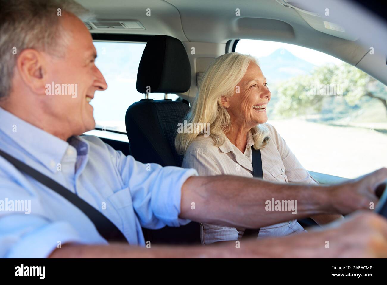 Happy senior white couple driving in their car, smiling, side view, close up Stock Photo