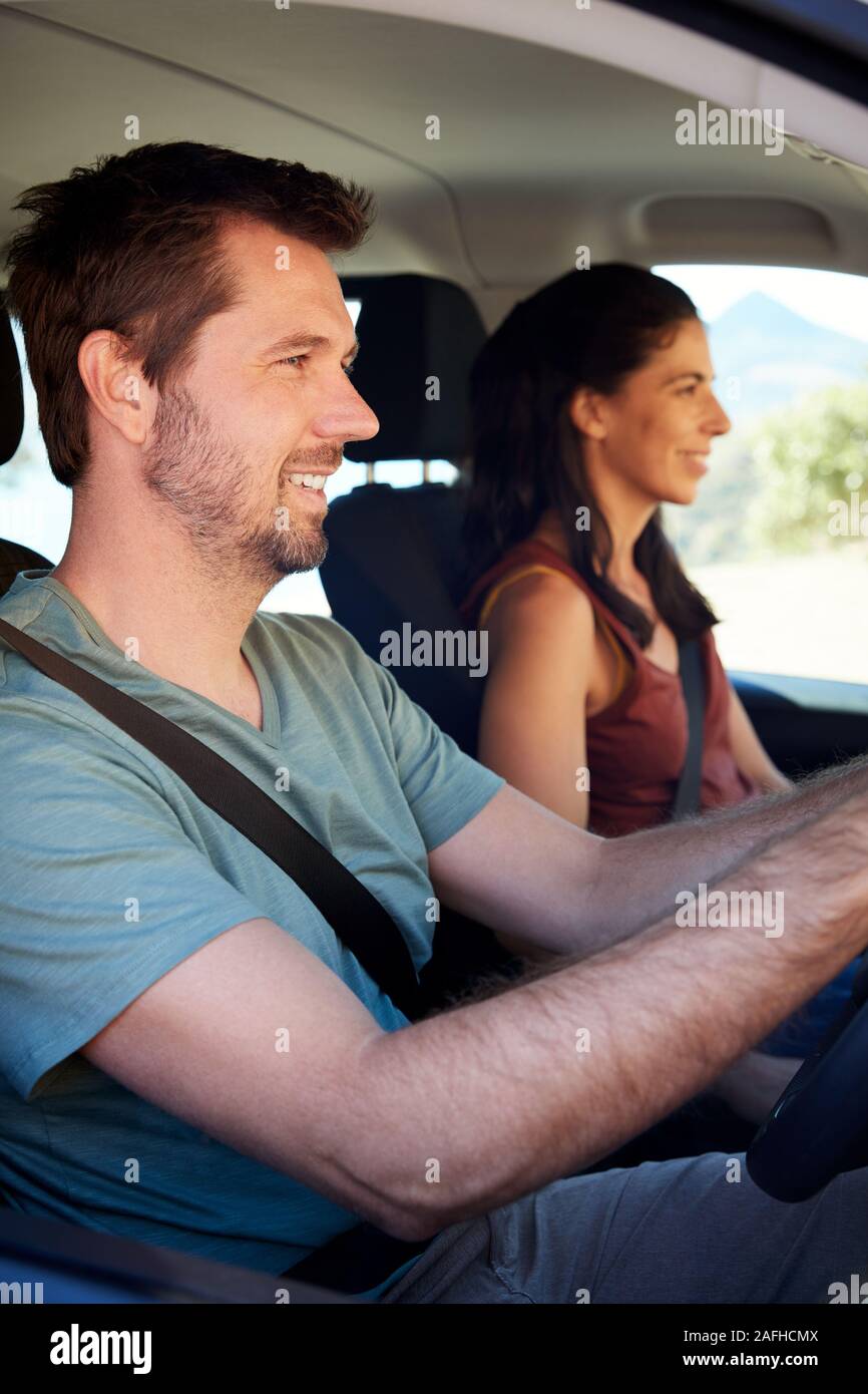 Smiling mid adult white couple driving in their car, close up, side view, vertical Stock Photo