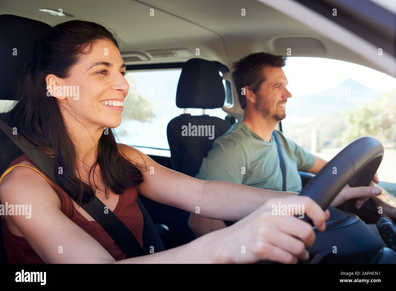 Mid adult white woman driving car, husband beside her in front passenger seat, close up, side view Stock Photo