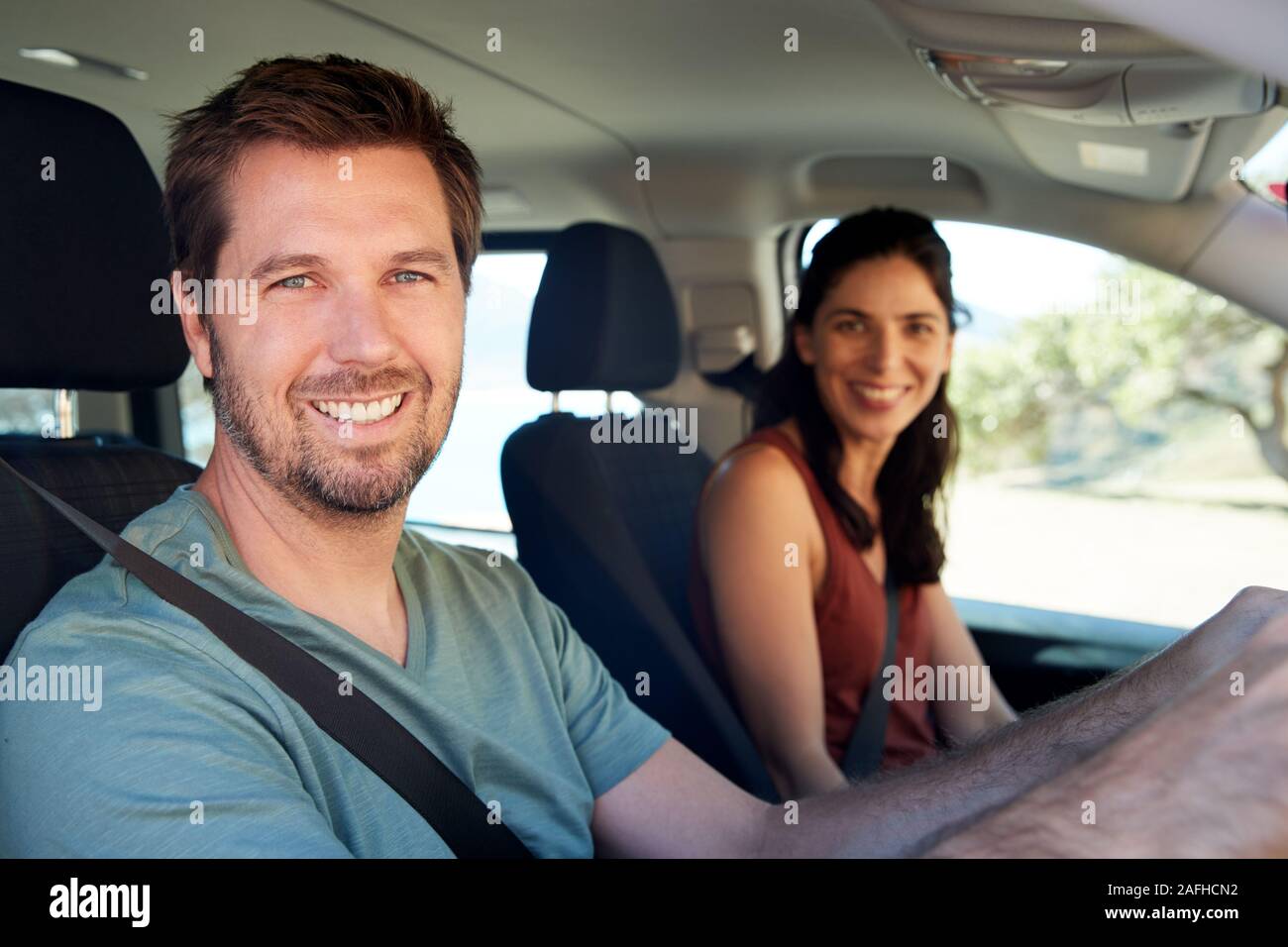Smiling mid adult white couple driving in their car smiling to camera, close up, side view Stock Photo