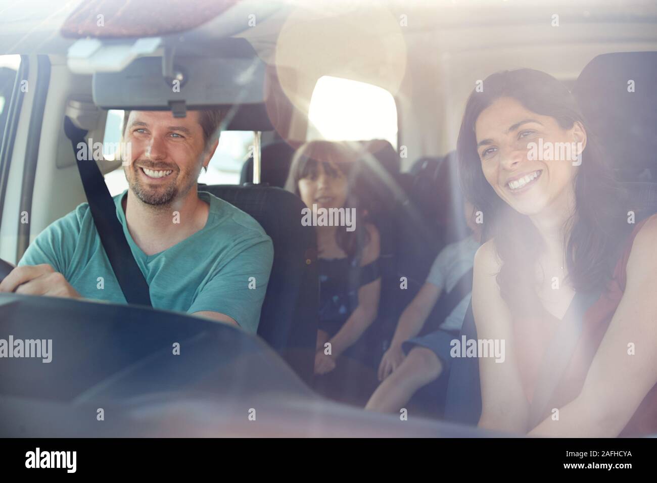 Young white family of four setting off on a journey in their car, seen through front windscreen Stock Photo