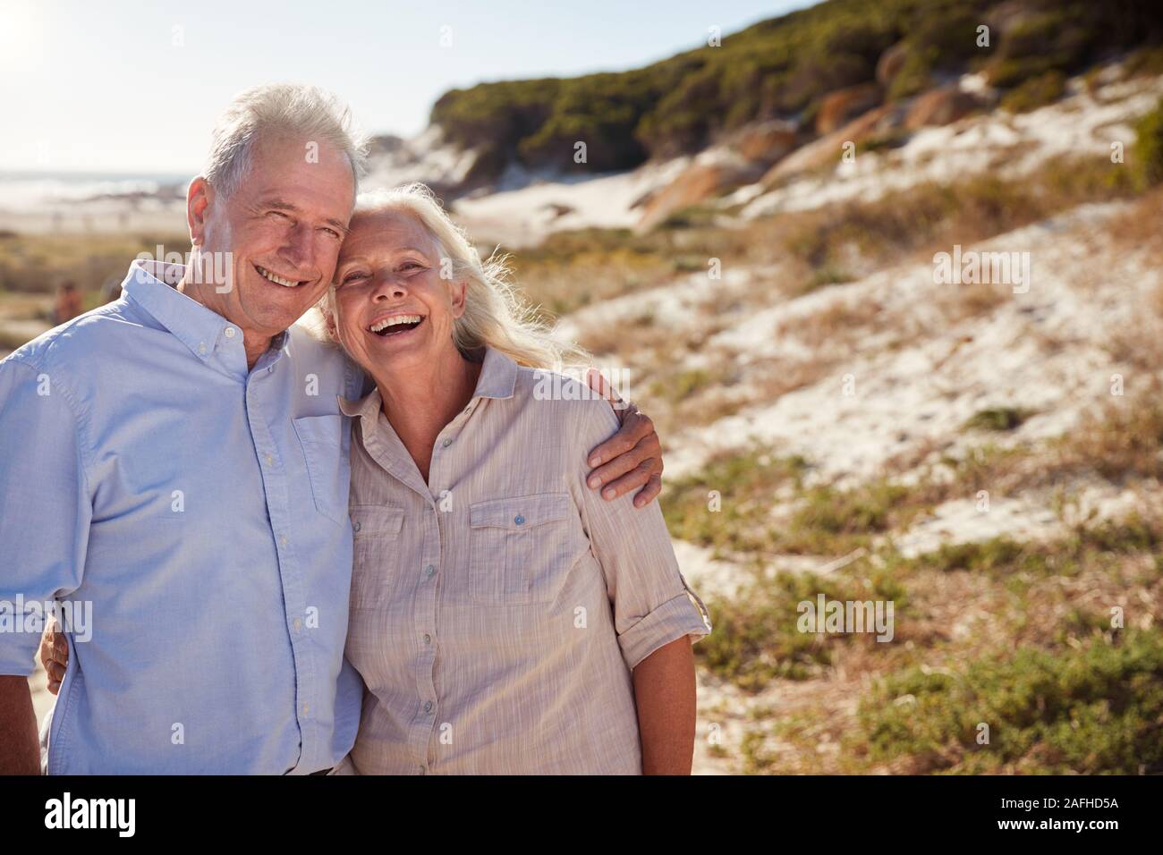 Senior white couple standing on a beach embracing and smiling to camera, close up Stock Photo