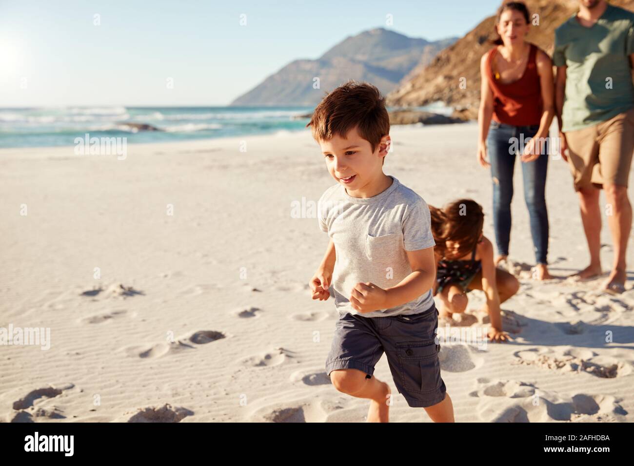 Happy young white family on holiday exploring a beach together, full length, close up Stock Photo