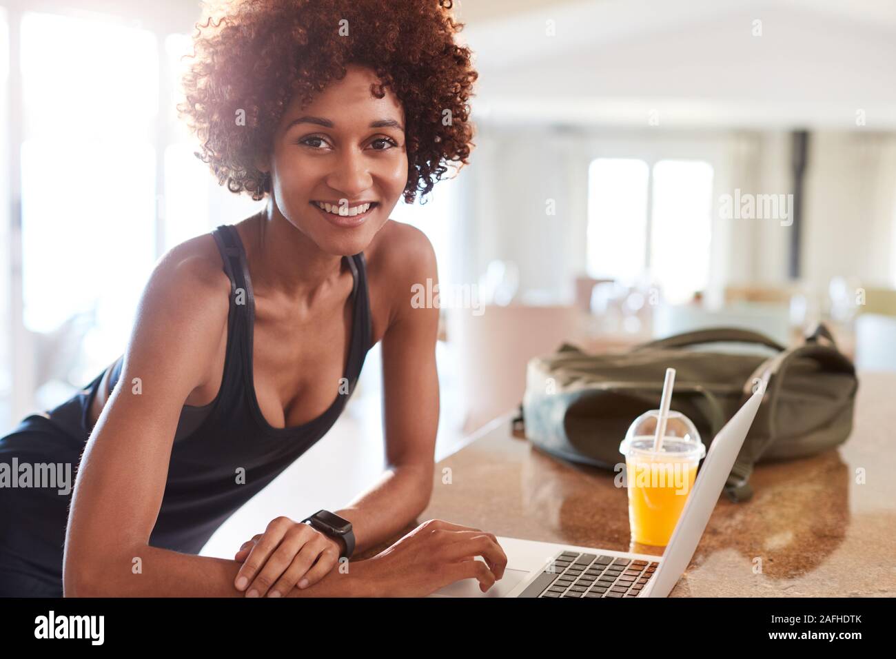 Millennial African American woman checking fitness data on laptop after gym smiling to camera Stock Photo