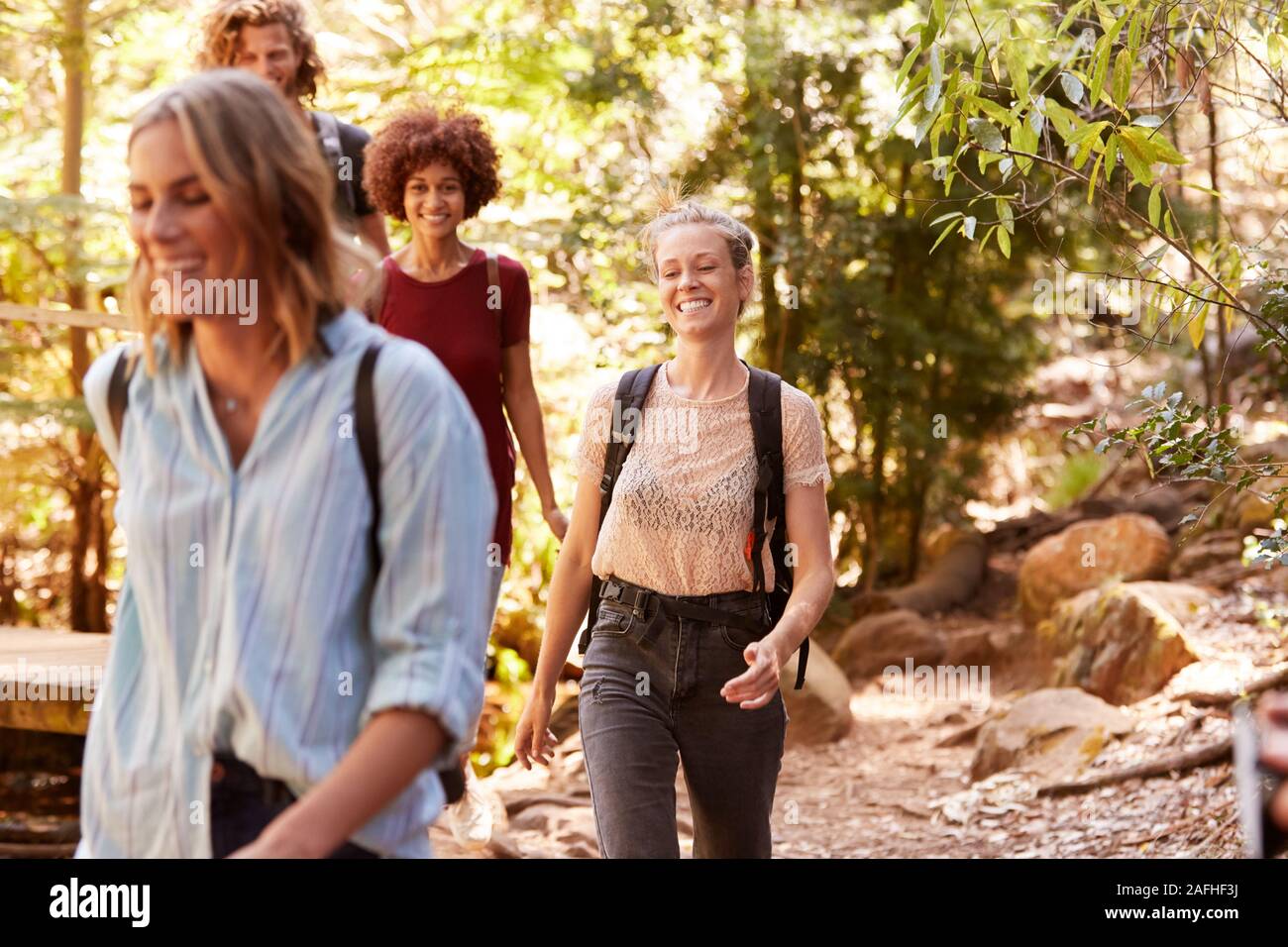 Smiling millennial girlfriends walking together during a hike in a forest, close up Stock Photo