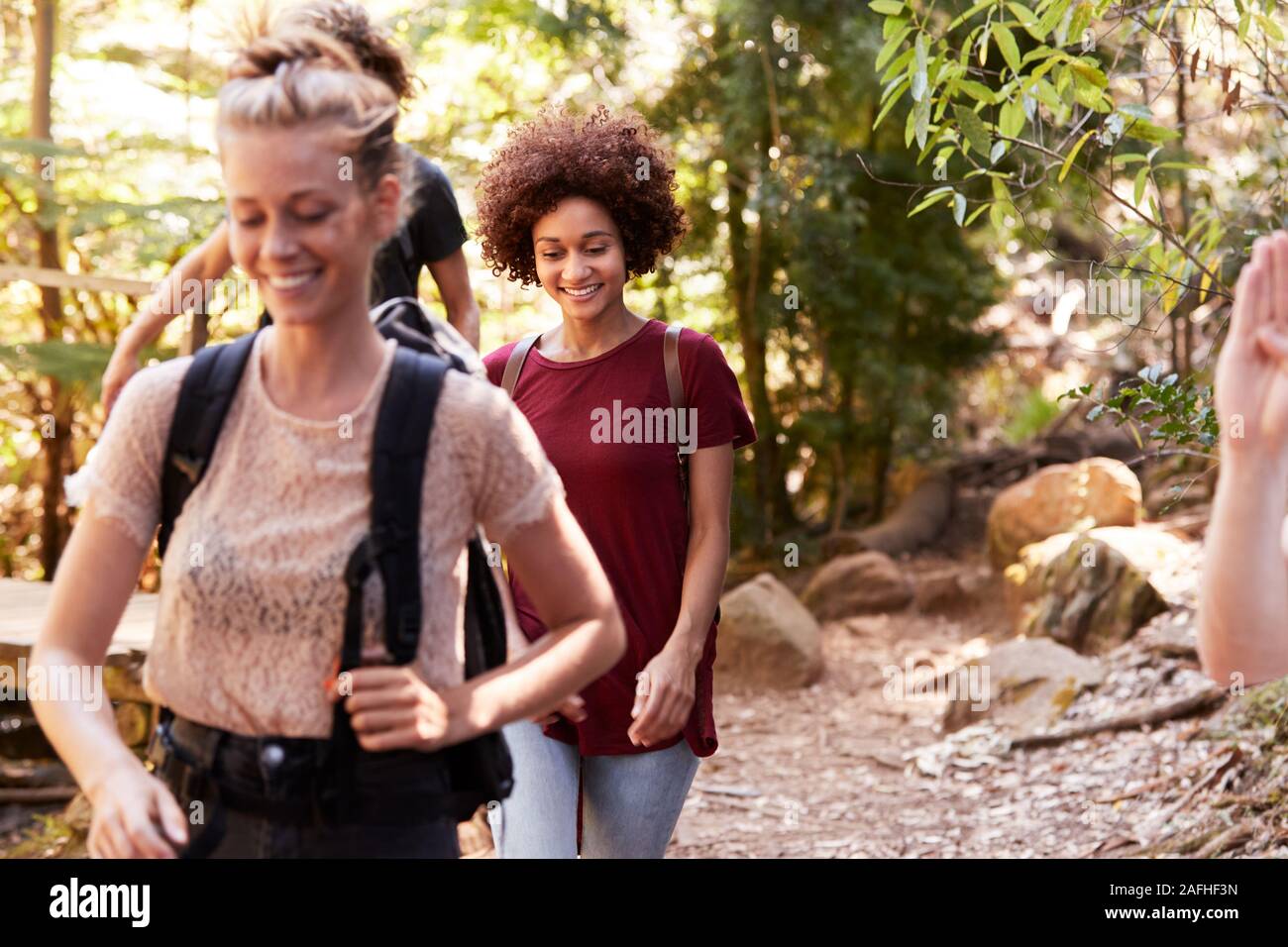 Millennial girlfriends walking together during a hike in a forest, close up Stock Photo
