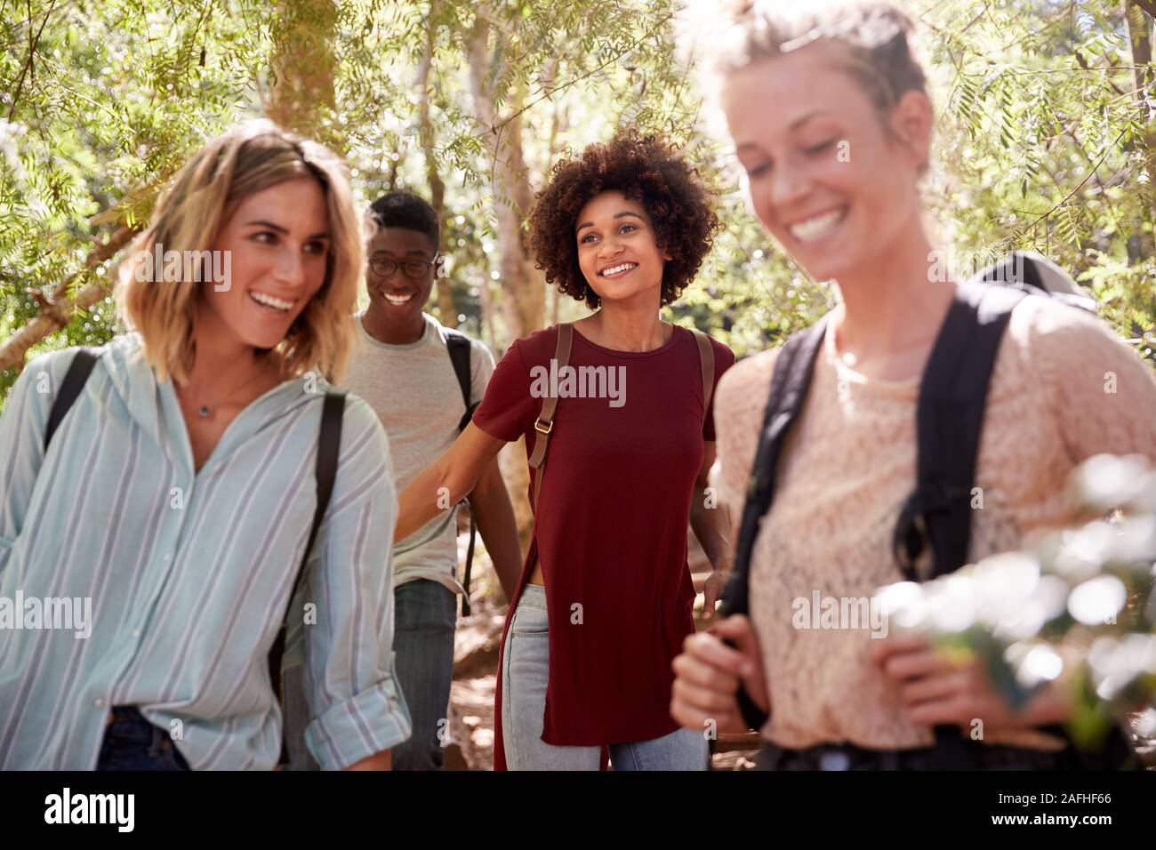 Young adult friends hiking in a forest laughing together, close up Stock Photo