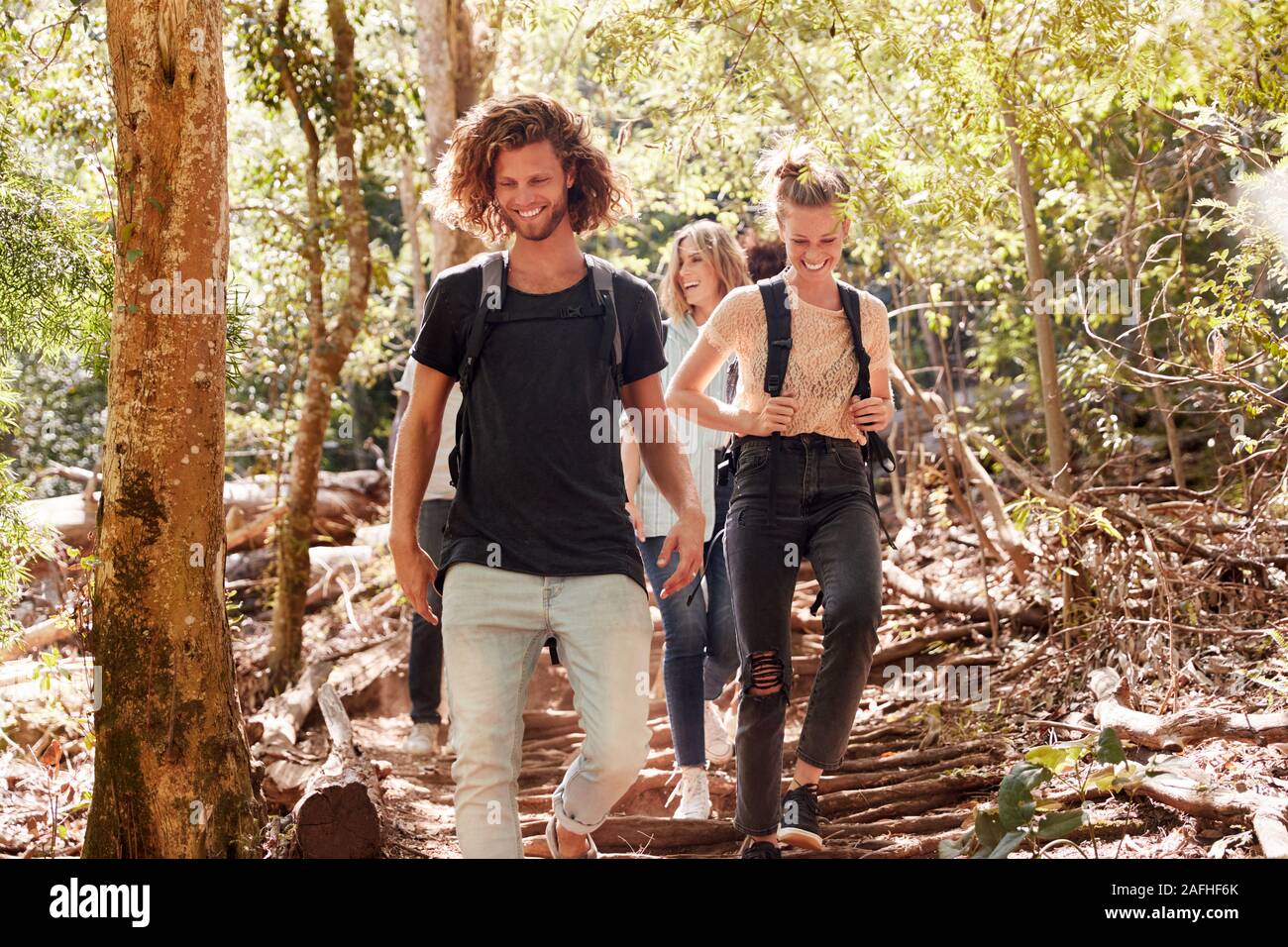 Millennial friends hiking together downhill on a forest trail, full length Stock Photo
