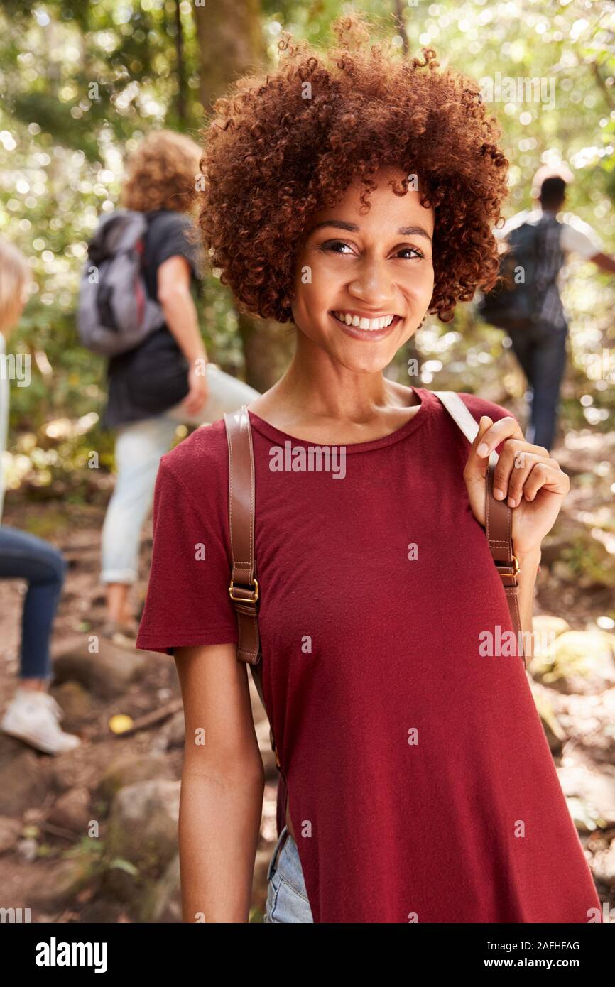 Smiling millennial African American woman hiking in a forest, waist up, close up, vertical Stock Photo