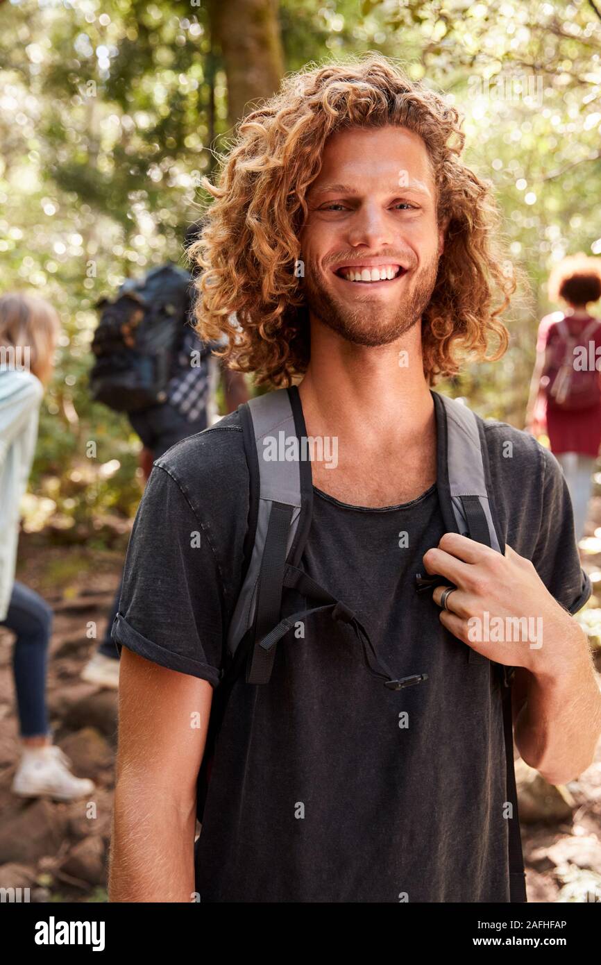 Waist up portrait of smiling millennial white man hiking in a forest, close up, vertical Stock Photo