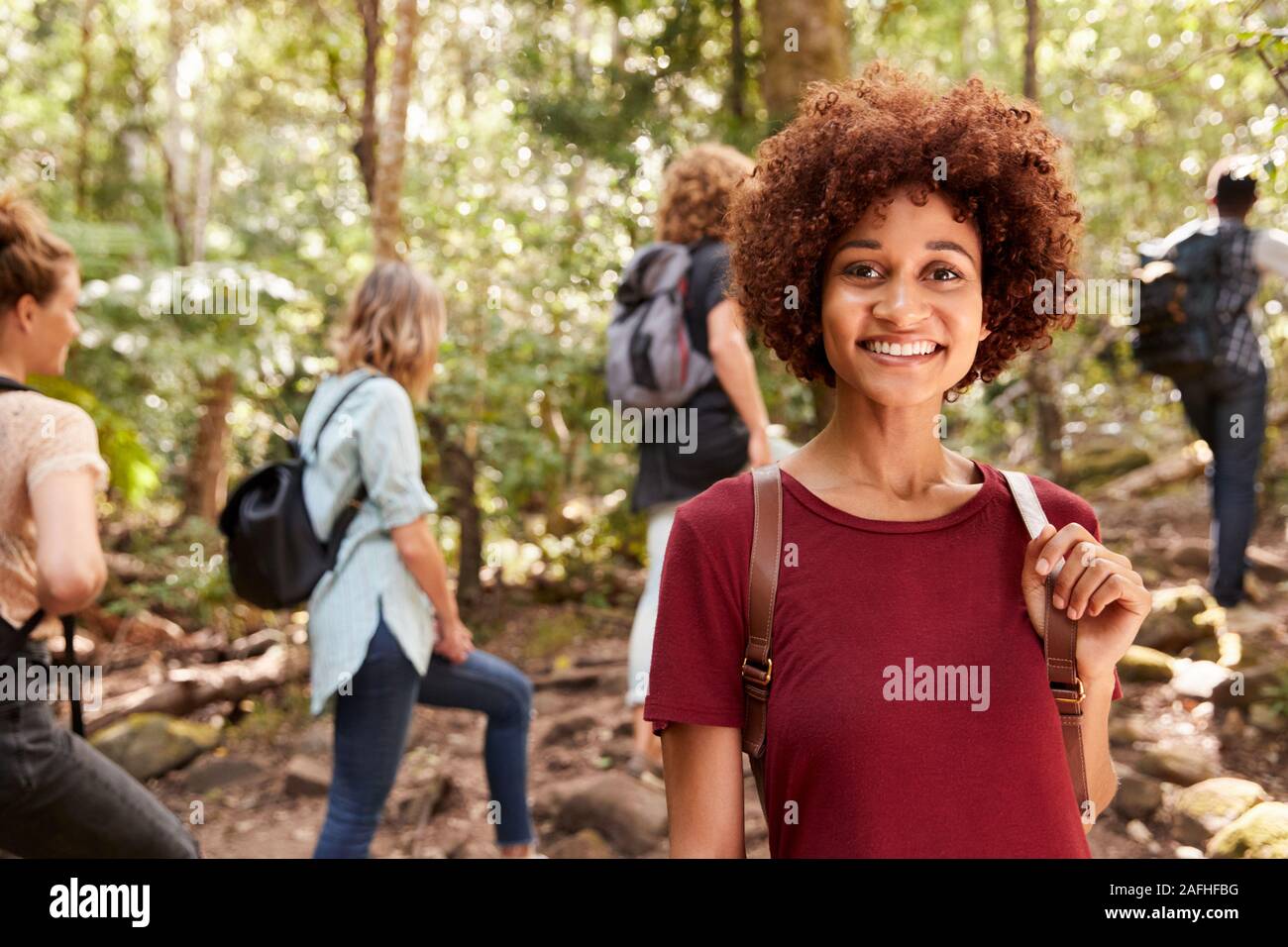 Smiling millennial African American woman hiking in a forest with friends, waist up, close up Stock Photo