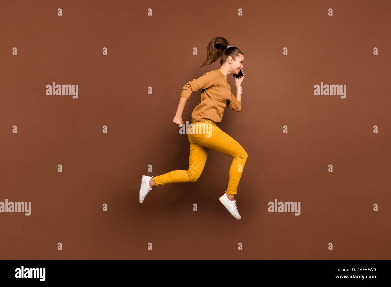 Full length body size side profile photo of young girl speaking by her phone running towards discounted shopping mall wearing trousers pants isolated Stock Photo
