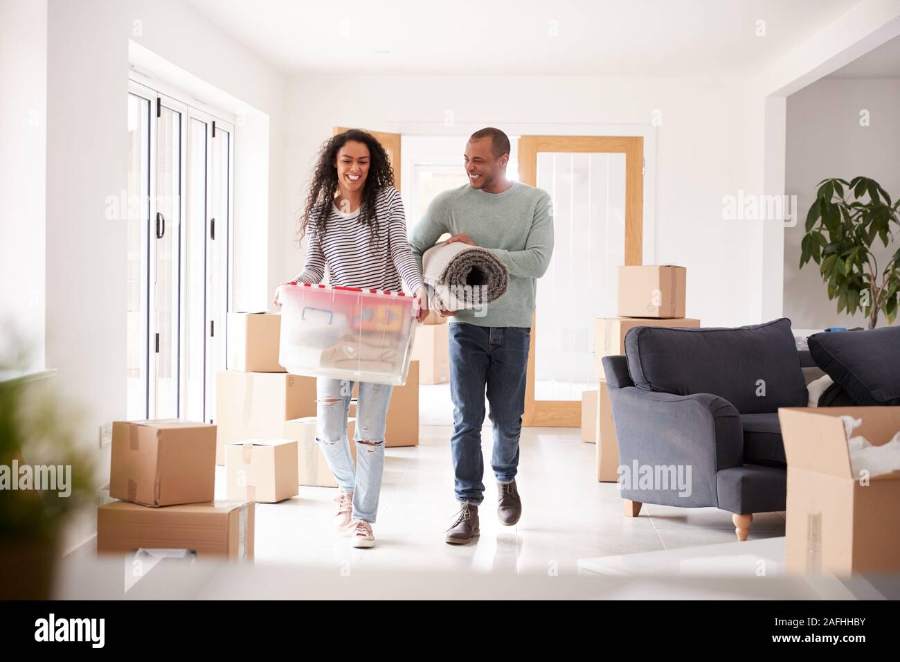 Smiling Couple Carrying Boxes Into New Home On Moving Day Stock Photo