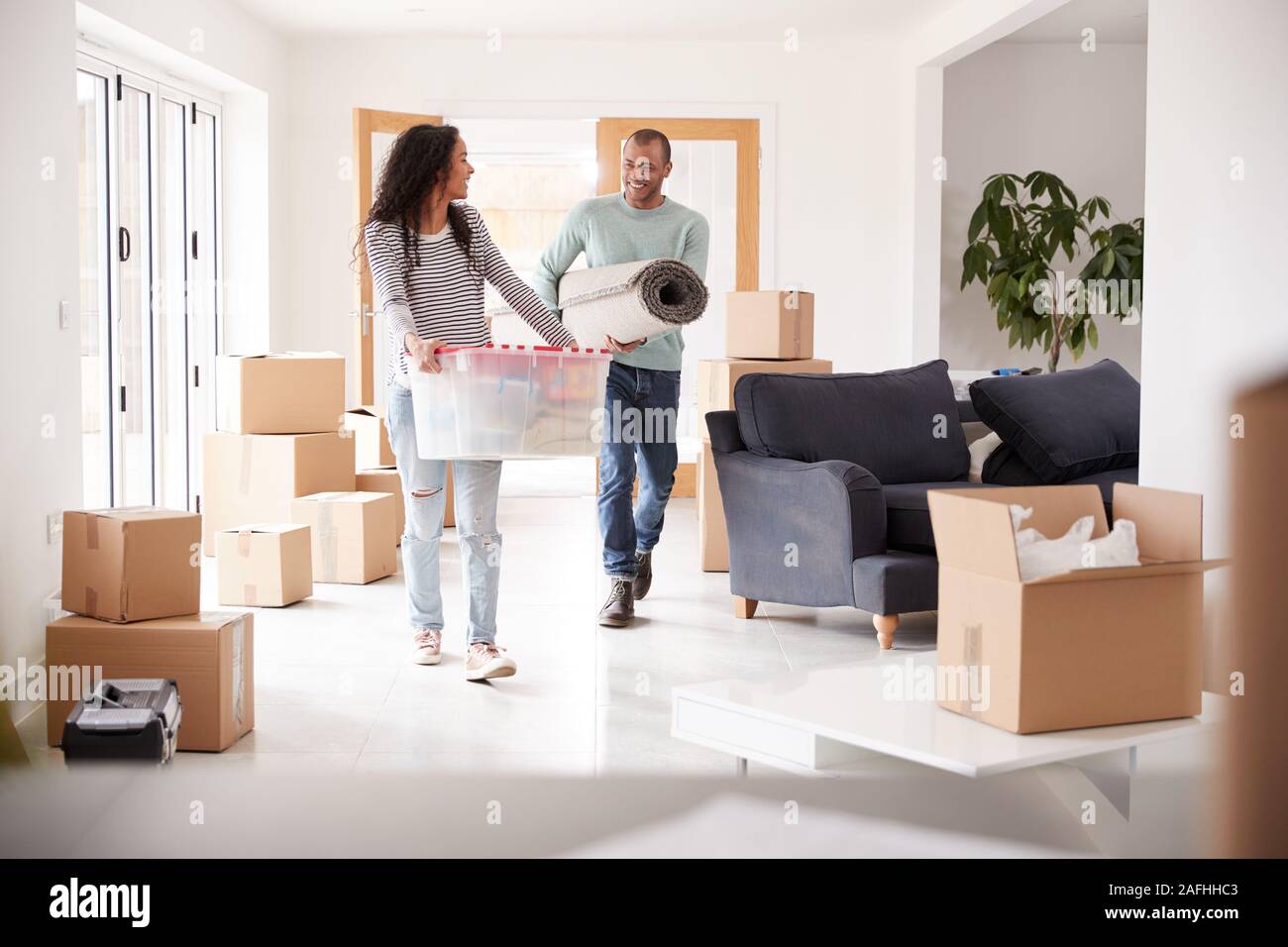 Smiling Couple Carrying Boxes Into New Home On Moving Day Stock Photo