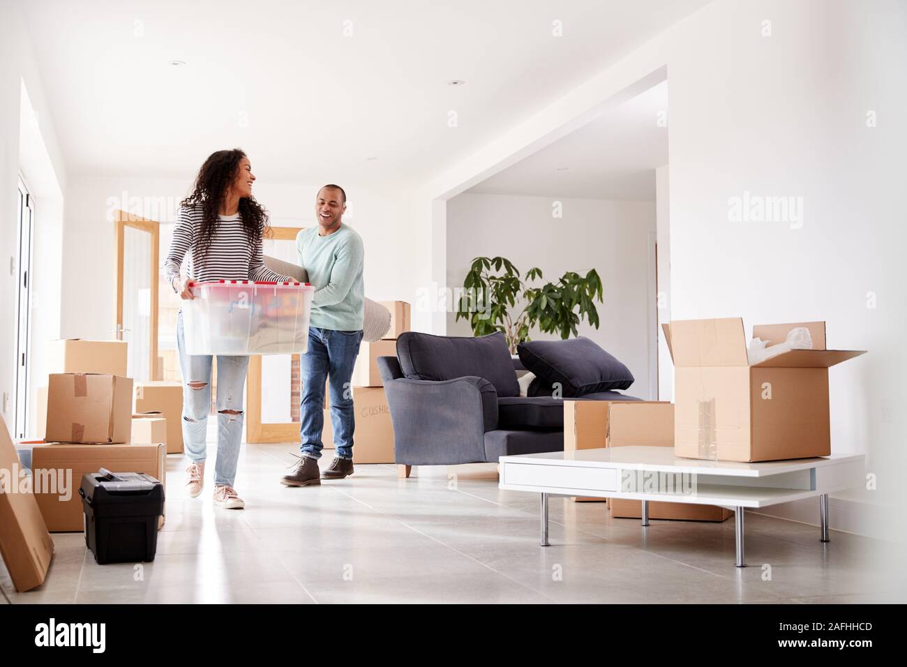 Smiling Couple Carrying Boxes Into New Home On Moving Day Stock Photo ...