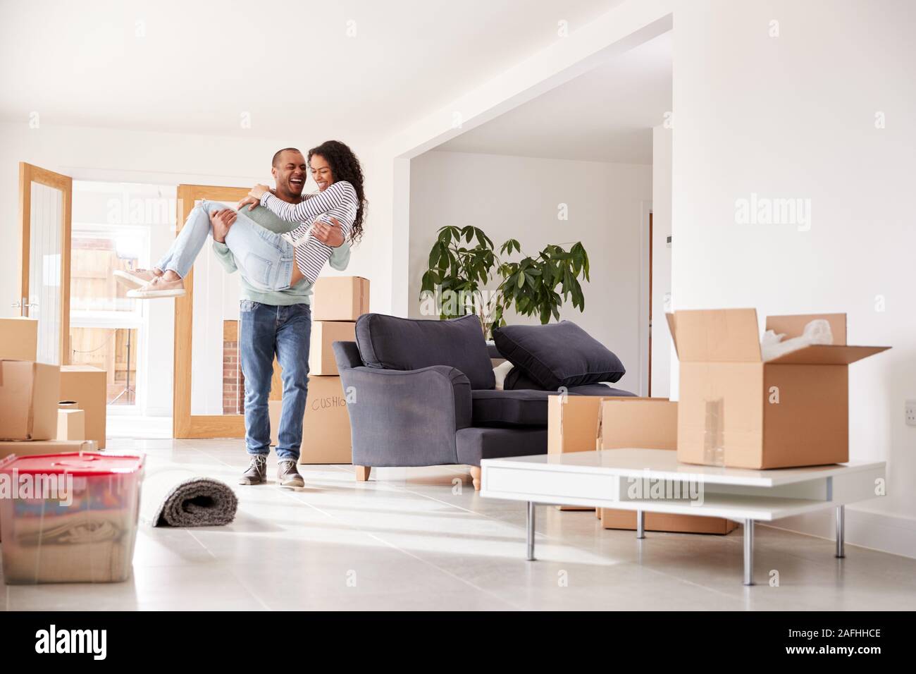 Man Carrying Woman Over Threshold Of New Home On Moving Day Stock Photo
