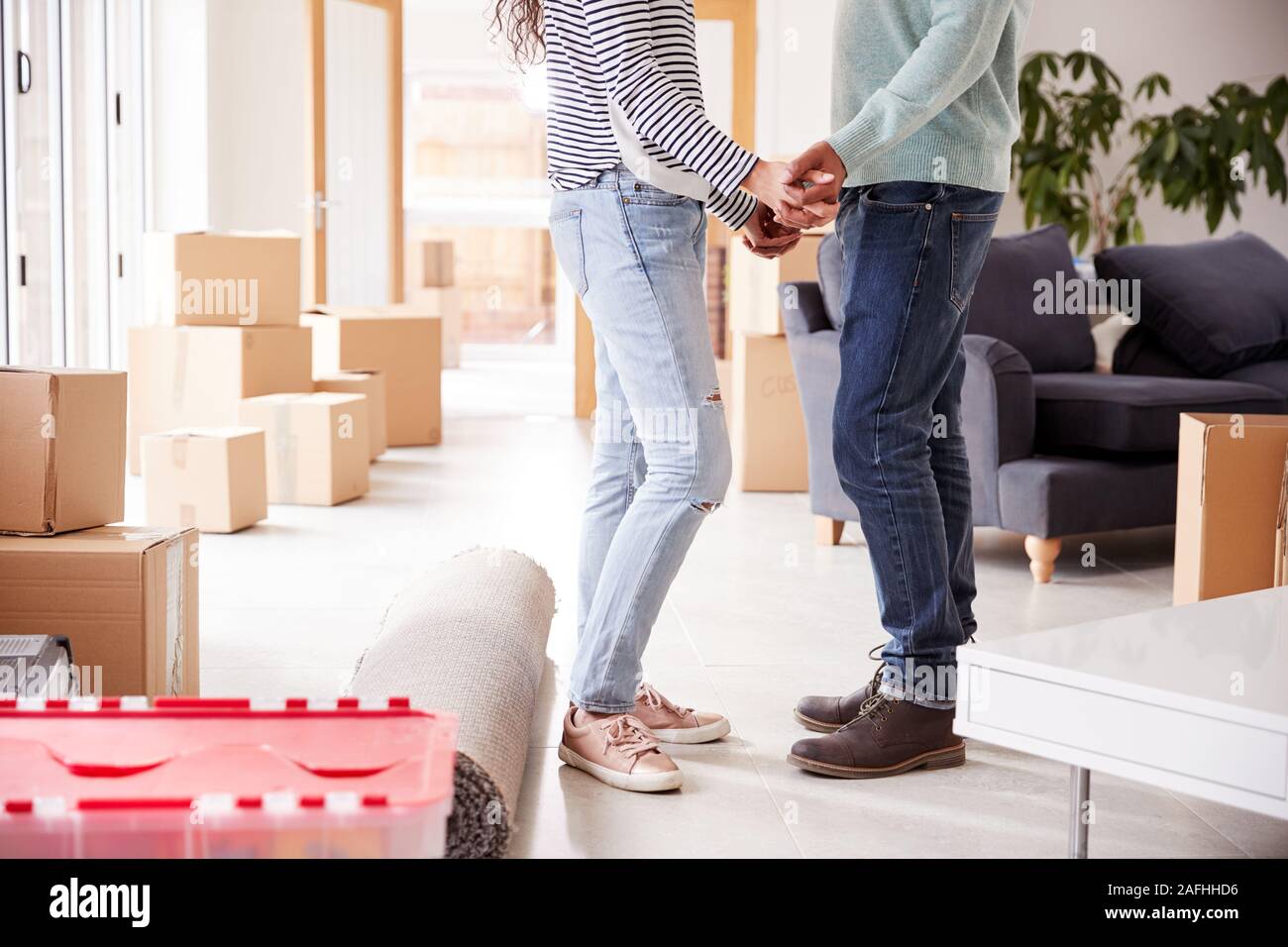 Close Up Of Loving Couple Holding Hands Surrounded By Boxes In New Home On Moving Day Stock Photo