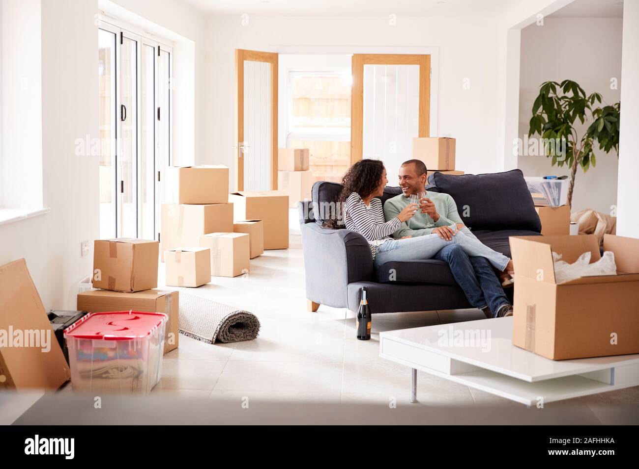 Couple Taking A Break And Sitting On Sofa Celebrating Moving Into New