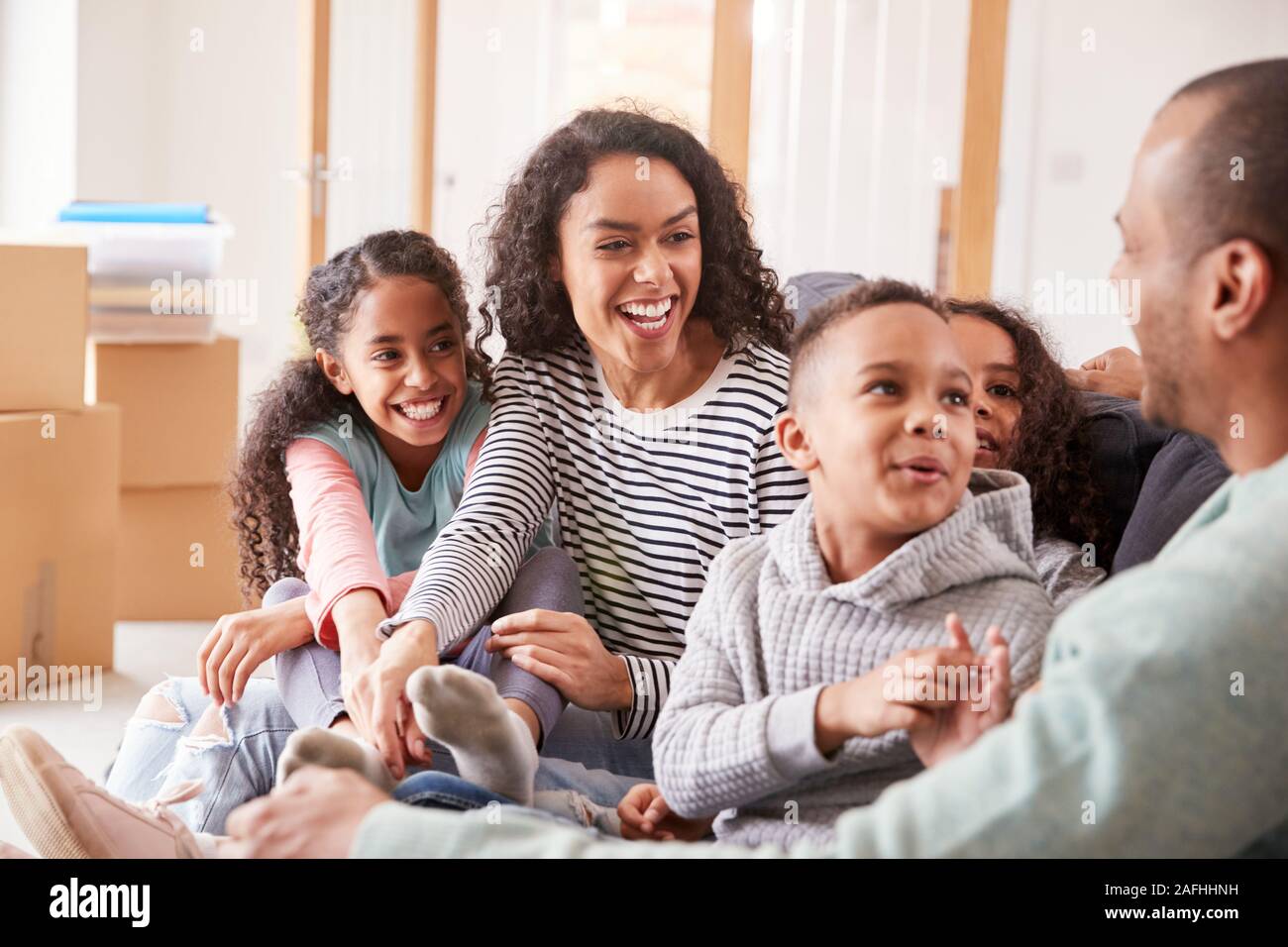 Family Taking A Break And Sitting On Sofa Celebrating Moving Into New Home Together Stock Photo