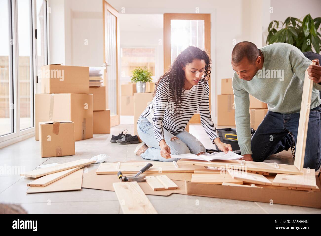 Couple In New Home On Moving Day Putting Together Self Assembly