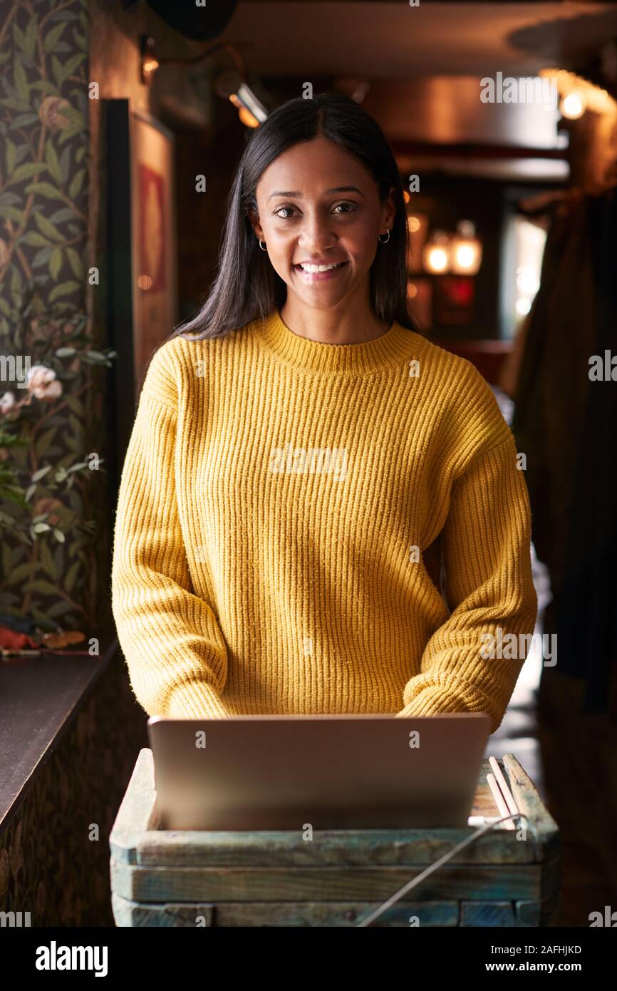 Portrait Of Female Receptionist Working On Laptop At Hotel Check In Stock Photo