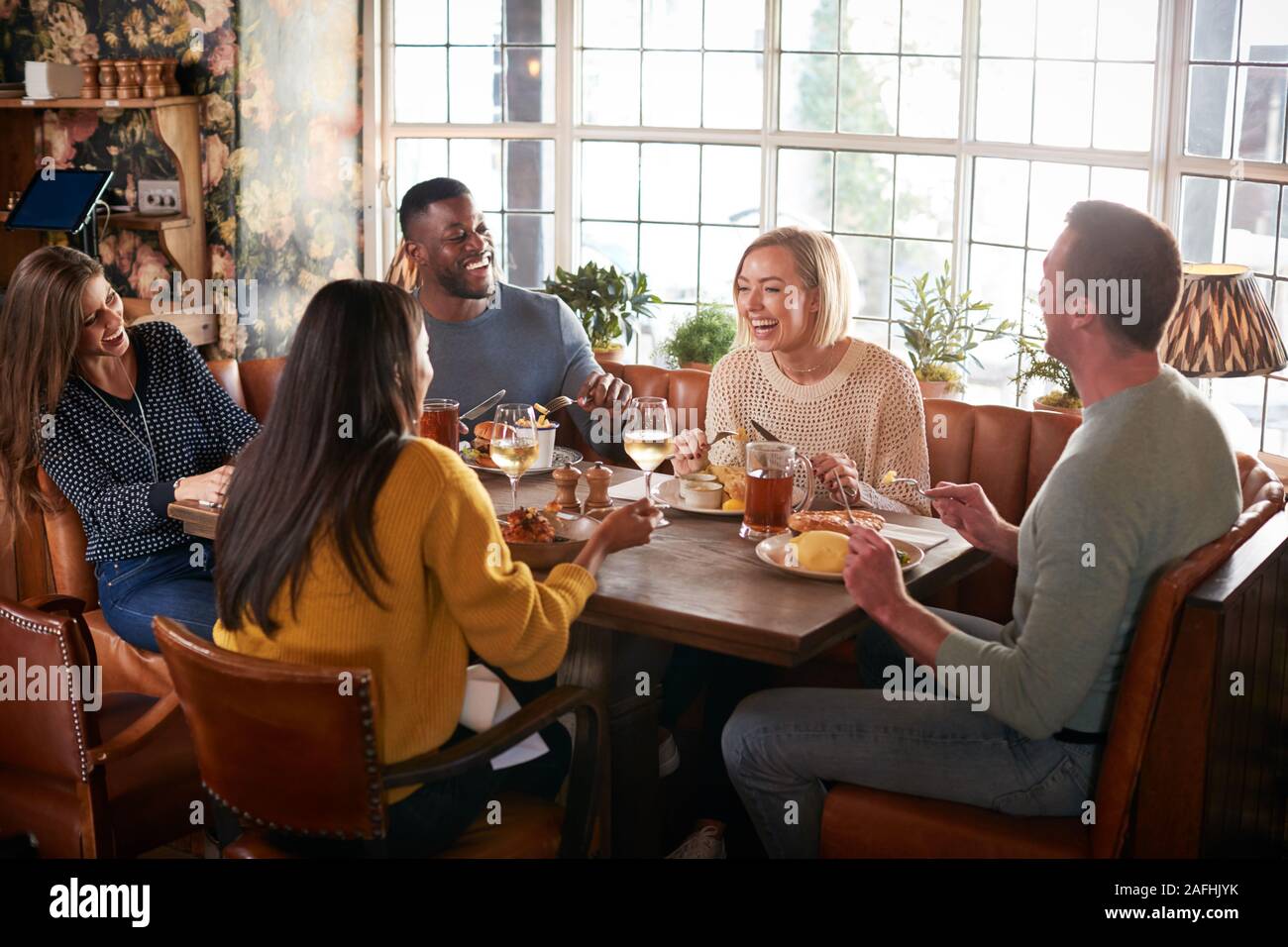 Group Of Friends Meeting For Meal In Traditional English Pub Stock Photo