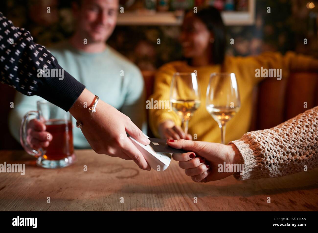 Close Up Of Customer Paying In Hotel Restaurant Using Contactless Card Reader Stock Photo