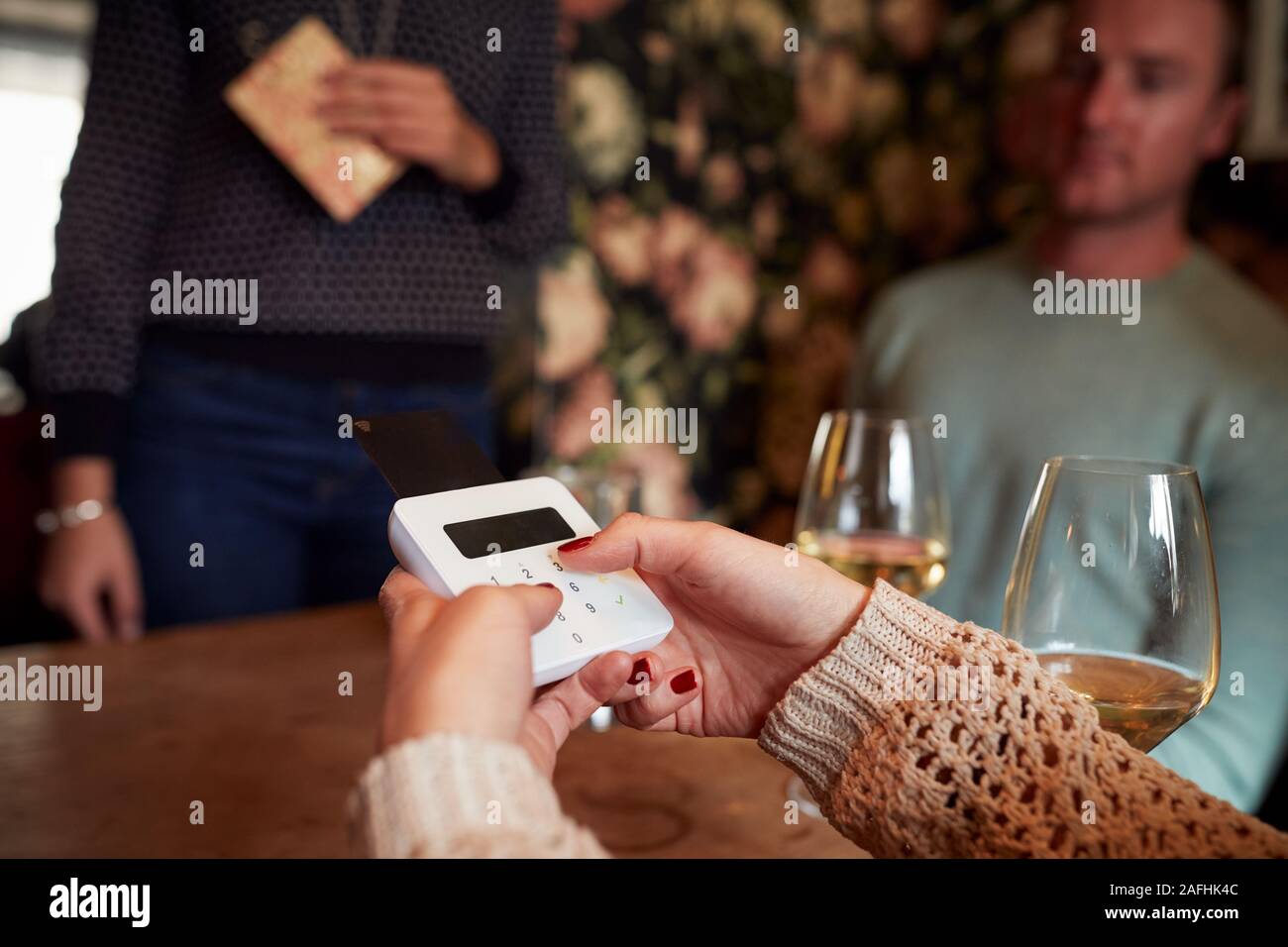 Close Up Of Customer In Restaurant Entering PIN Number Into Credit Card Terminal Stock Photo