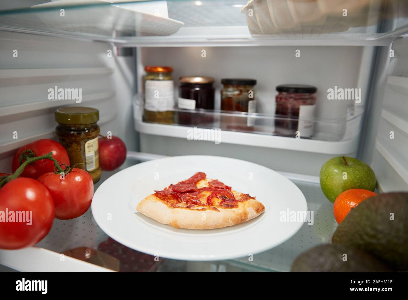 View Inside Refrigerator Of Leftover Takeaway Pizza Slice On Shelf Stock Photo