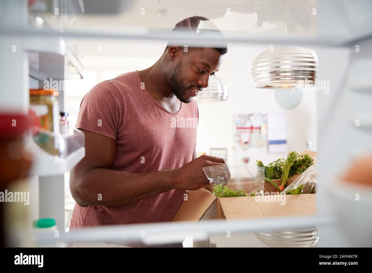 View Looking Out From Inside Of Refrigerator As Man Unpacks Online Home Food Delivery Stock Photo