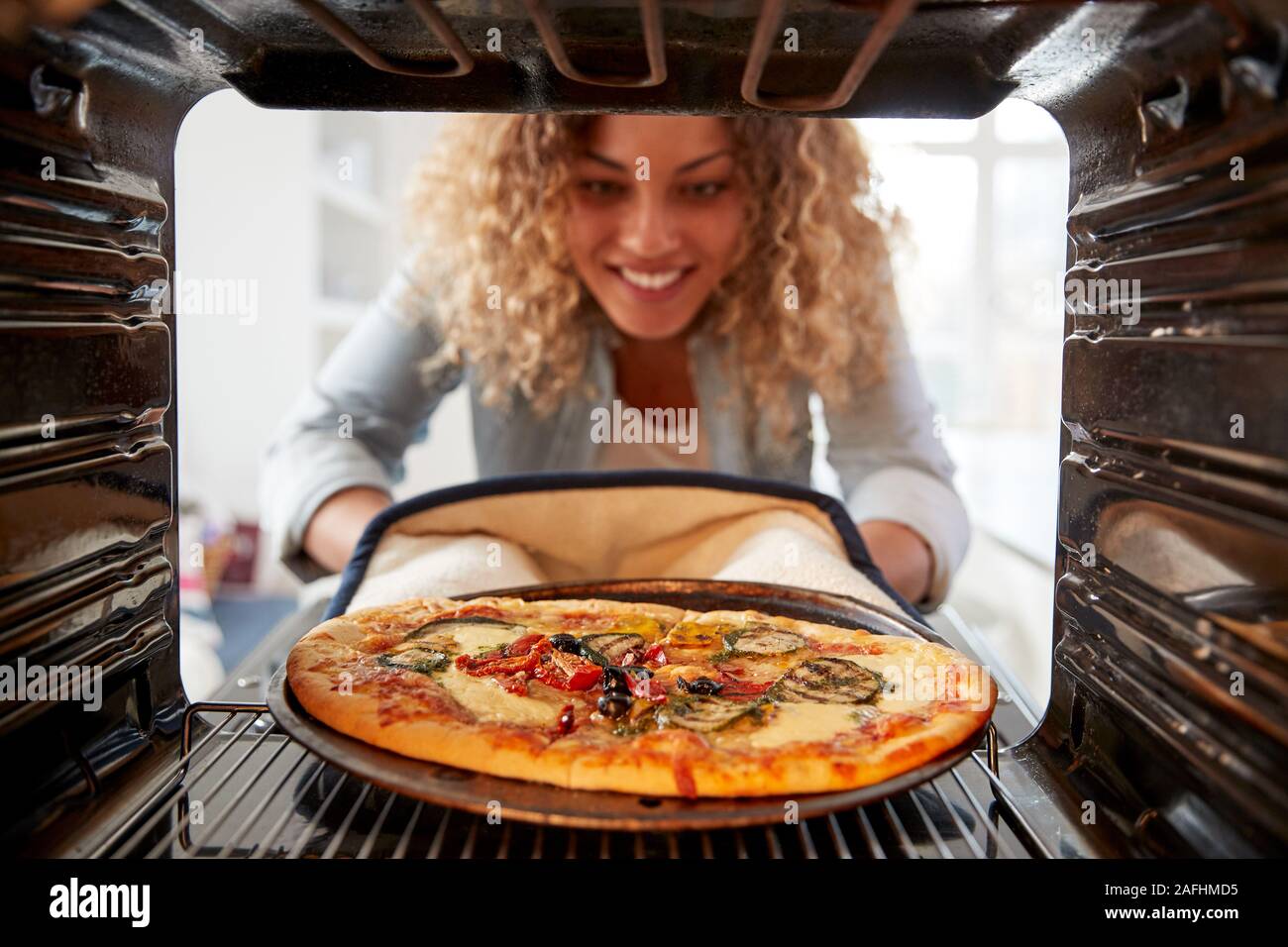 View Looking Out From Inside Oven As Woman Cooks Fresh Pizza Stock Photo