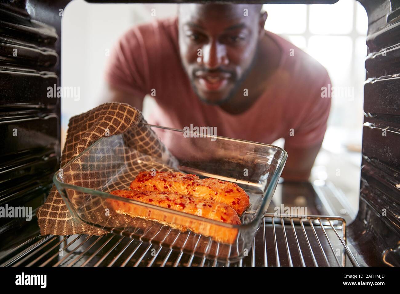View Looking Out From Inside Oven As Man Cooks Oven Baked Salmon Stock Photo