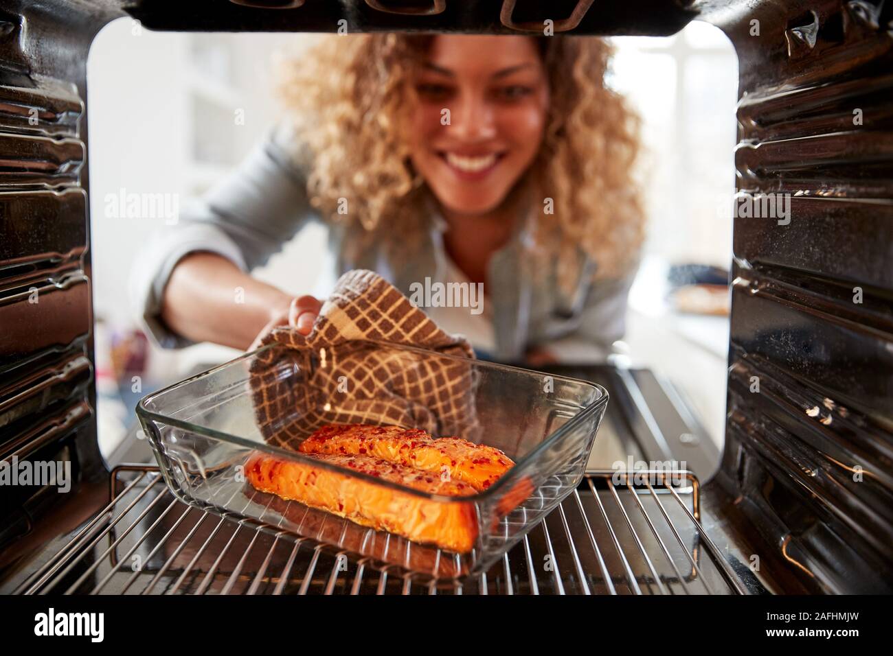 View Looking Out From Inside Oven As Woman Cooks Oven Baked Salmon Stock Photo