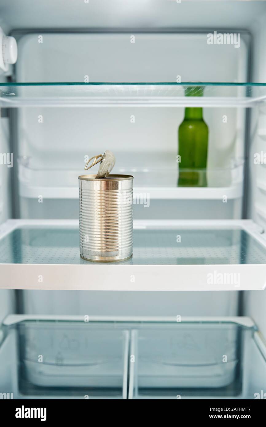 View Looking Inside Refrigerator Empty Except For Open Tin Can And Bottle Of Beer On Shelf Stock Photo