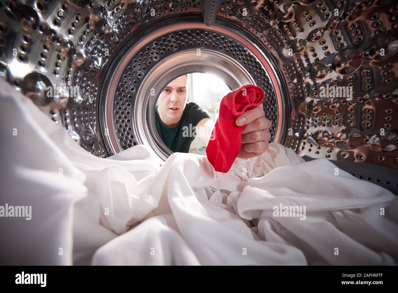 Man Taking Out Red Sock Mixed With White Laundry From Washing Machine Stock Photo